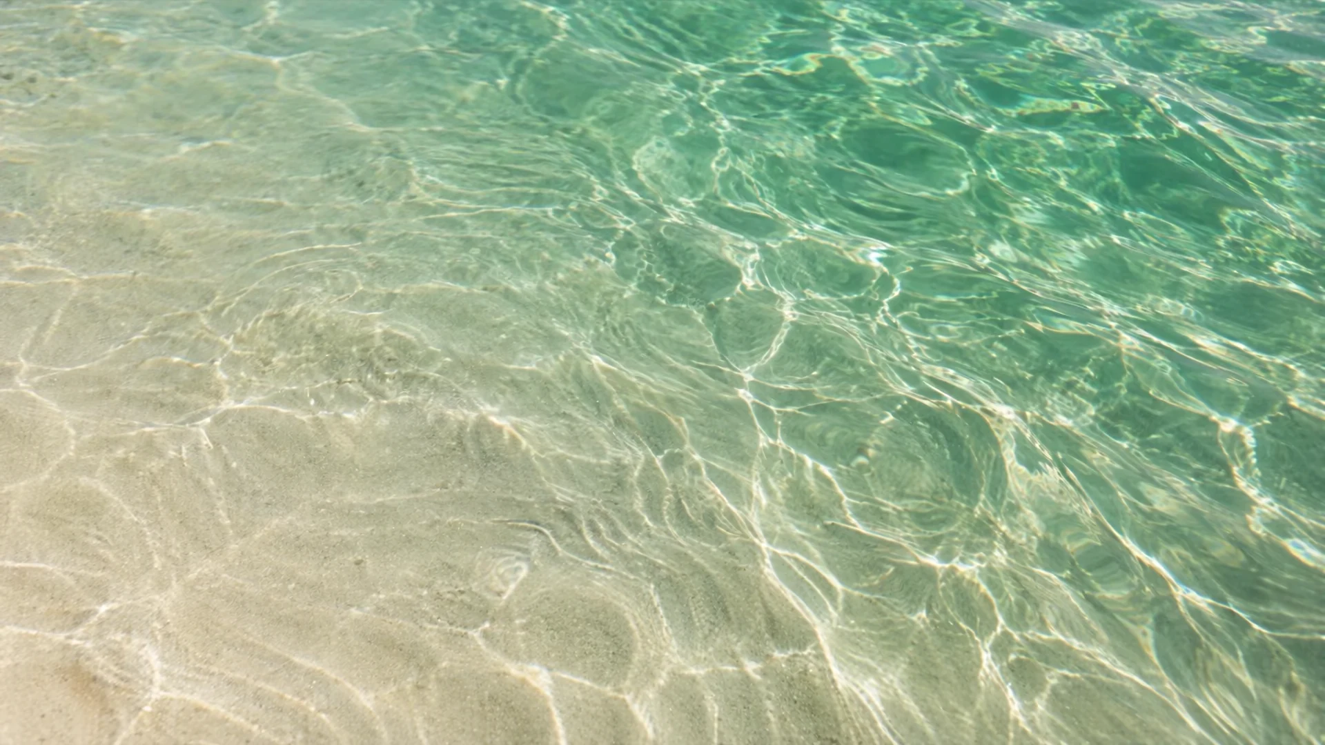 Sunlight moving across clear emerald water