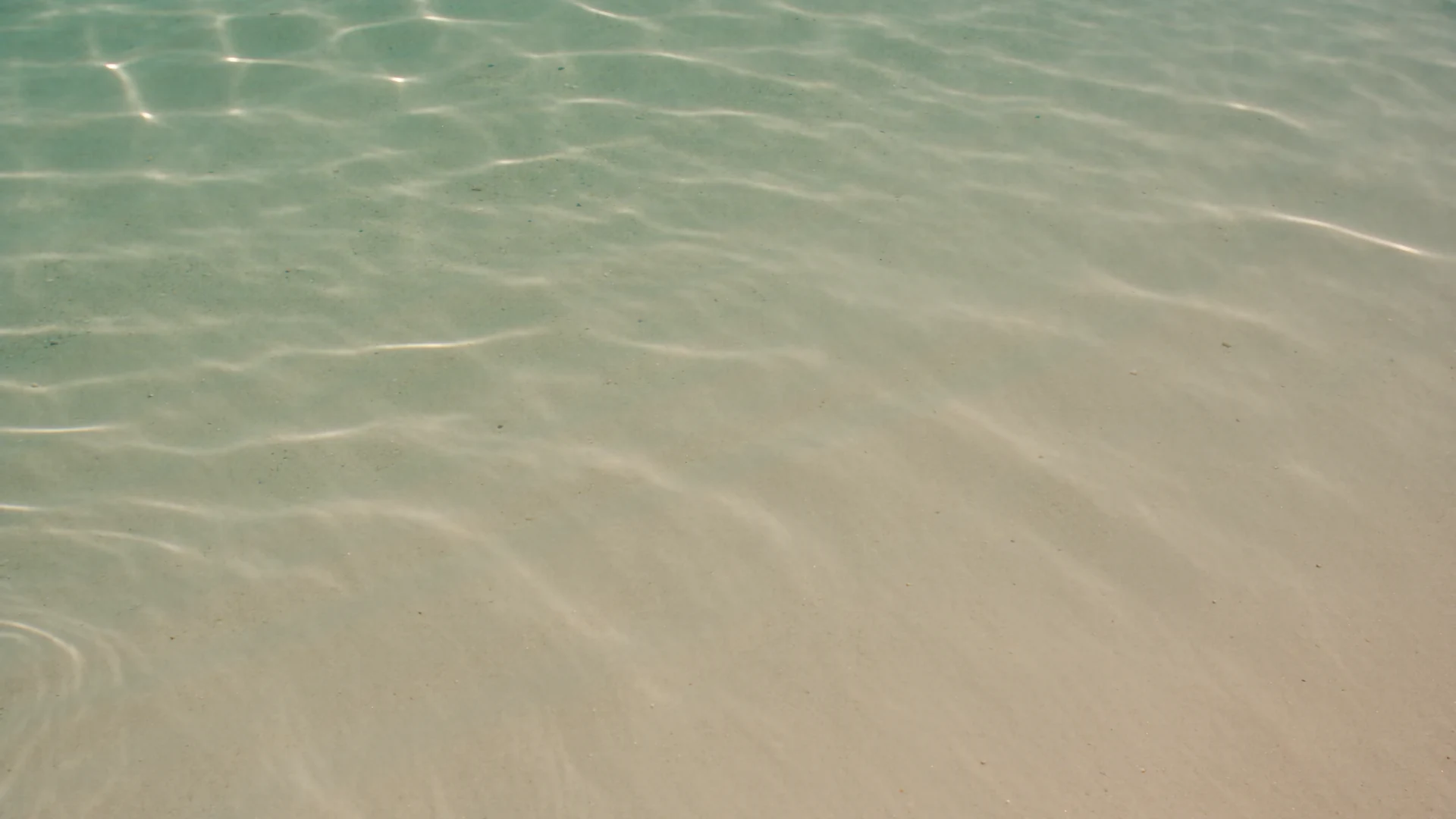 Sunlight moving across clear emerald water